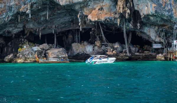 Explore the stunning sea cave with motorboats docked nearby, showcasing a perfect travel destination.