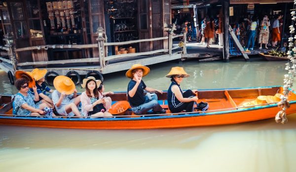 A group of tourists in a boat at a vibrant floating market in Thailand, exploring local culture.